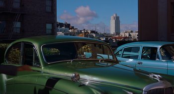 Movie still from “Vertigo” (1958), directed by Alfred Hitchcock – An old green car parked in a parking lot; Wide shot, Low angle