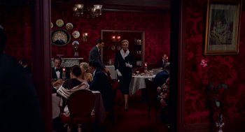 Movie still from “Vertigo” (1958), directed by Alfred Hitchcock – A group of diners at a restaurant with a woman in a black dress; Wide shot, High angle