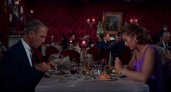 Movie still from “Vertigo” (1958), directed by Alfred Hitchcock – Two people sitting at a dinner table with wine glasses; Wide shot, Over the shoulder angle