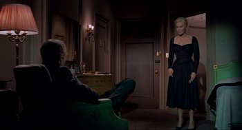 Movie still from “Vertigo” (1958), directed by Alfred Hitchcock – A man and a woman are in a dark room; Wide shot, High angle