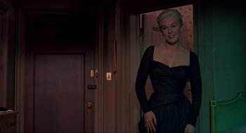 Movie still from “Vertigo” (1958), directed by Alfred Hitchcock – A woman in a black dress standing in front of a door; Medium shot, Low angle