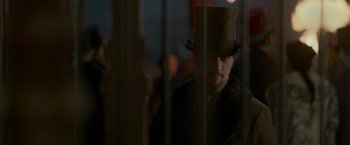 Movie still from “Victor Frankenstein” (2015), directed by Paul McGuigan – A man wearing a top hat standing behind bars; Close Up shot, Over the shoulder angle