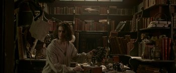 Movie still from “Victor Frankenstein” (2015), directed by Paul McGuigan – A man sitting at a desk in a library; Medium shot, Low angle