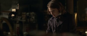 Movie still from “Victor Frankenstein” (2015), directed by Paul McGuigan – A man in a suit and tie looking down; Medium shot, Over the shoulder angle