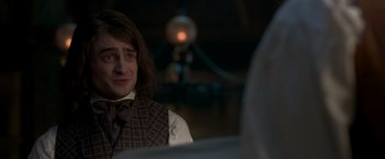 Movie still from “Victor Frankenstein” (2015), directed by Paul McGuigan – A man with long brown hair wearing a vest; Close Up shot, Over the shoulder angle