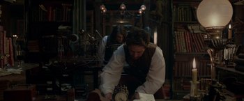 Movie still from “Victor Frankenstein” (2015), directed by Paul McGuigan – A man in white shirt and brown vest looking at a clock; Medium shot, Low angle