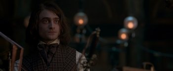 Movie still from “Victor Frankenstein” (2015), directed by Paul McGuigan – A man with long brown hair wearing a vest and a tie; Close Up shot, Over the shoulder angle