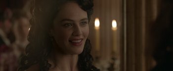Movie still from “Victor Frankenstein” (2015), directed by Paul McGuigan – A beautiful woman with long dark curly hair and green eyes; Close Up shot, Over the shoulder angle