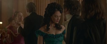 Movie still from “Victor Frankenstein” (2015), directed by Paul McGuigan – A woman in a green dress standing in front of a wall; Medium shot, Over the shoulder angle