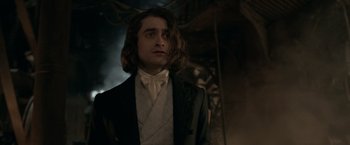 Movie still from “Victor Frankenstein” (2015), directed by Paul McGuigan – A man in a suit and tie standing in front of a building; Close Up shot, Over the shoulder angle