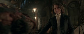 Movie still from “Victor Frankenstein” (2015), directed by Paul McGuigan – A man in a suit and tie standing next to a lamp post; Medium shot, Over the shoulder angle