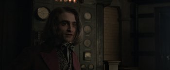 Movie still from “Victor Frankenstein” (2015), directed by Paul McGuigan – A man with long hair wearing a suit and tie; Medium shot, Over the shoulder angle