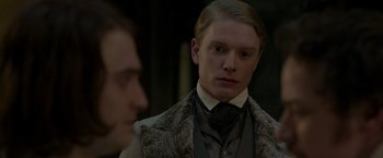 Movie still from “Victor Frankenstein” (2015), directed by Paul McGuigan – A man in a suit and tie standing next to another man in a suit; Close Up shot, Over the shoulder angle