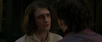 Movie still from “Victor Frankenstein” (2015), directed by Paul McGuigan – A man with long hair and a beard is talking to another man; Close Up shot, Over the shoulder angle