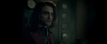 Movie still from “Victor Frankenstein” (2015), directed by Paul McGuigan – A man with long dark hair wearing a red jacket; Close Up shot, Over the shoulder angle