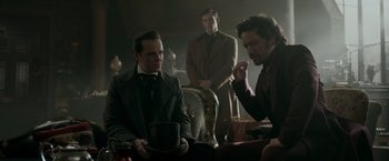 Movie still from “Victor Frankenstein” (2015), directed by Paul McGuigan – A group of men sitting in a room together; Medium shot, Over the shoulder angle