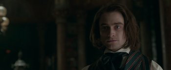 Movie still from “Victor Frankenstein” (2015), directed by Paul McGuigan – A man with long brown hair wearing a black bow tie; Close Up shot, Over the shoulder angle