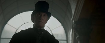 Movie still from “Victor Frankenstein” (2015), directed by Paul McGuigan – An older man wearing a top hat and a suit; Close Up shot, Low angle