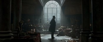 Movie still from “Victor Frankenstein” (2015), directed by Paul McGuigan – A man standing in front of a window in a dark room; Wide shot, Low angle