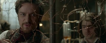 Movie still from “Victor Frankenstein” (2015), directed by Paul McGuigan – A man standing in front of a glass of wine; Close Up shot, Over the shoulder angle