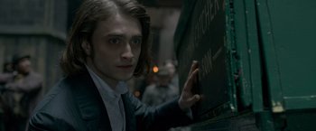 Movie still from “Victor Frankenstein” (2015), directed by Paul McGuigan – A man in a suit and tie leaning against a wall; Close Up shot, Over the shoulder angle