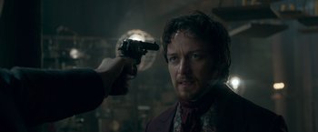Movie still from “Victor Frankenstein” (2015), directed by Paul McGuigan – A man holding a gun up to his face; Close Up shot, Over the shoulder angle