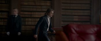 Movie still from “Victor Frankenstein” (2015), directed by Paul McGuigan – A man in a suit and tie walking in a library; Medium shot, Over the shoulder angle