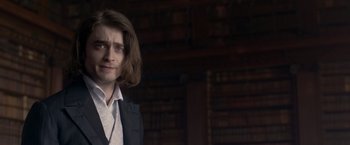 Movie still from “Victor Frankenstein” (2015), directed by Paul McGuigan – A man with long hair standing in front of a bookshelf; Close Up shot, Over the shoulder angle