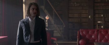 Movie still from “Victor Frankenstein” (2015), directed by Paul McGuigan – A man in a suit standing in a room; Medium shot, Over the shoulder angle