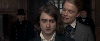 Movie still from “Victor Frankenstein” (2015), directed by Paul McGuigan – A man with long hair is standing next to another man with long hair; Close Up shot, Over the shoulder angle