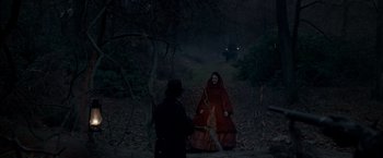 Movie still from “Victor Frankenstein” (2015), directed by Paul McGuigan – A woman in a red coat sitting on the ground in the dark; Wide shot, Over the shoulder angle