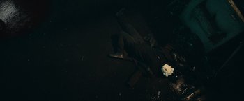 Movie still from “Vindicta” (2023), directed by Sean McNamara – A man is lying on the ground in the dark; Wide shot, Overhead angle