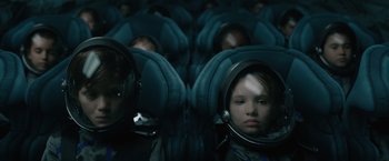 Movie still from “Voyagers” (2021), directed by Neil Burger – A young child is sitting in a seat in a space suit; Medium shot, Overhead angle