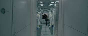 Movie still from “Voyagers” (2021), directed by Neil Burger – A group of people in white suits in a room; Wide shot, High angle