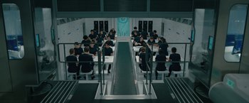 Movie still from “Voyagers” (2021), directed by Neil Burger – A group of people sitting at tables in a room; Wide shot, High angle