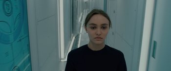 Movie still from “Voyagers” (2021), directed by Neil Burger – A young woman in a black shirt is standing in a hallway; Close Up shot, Low angle