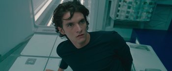 Movie still from “Voyagers” (2021), directed by Neil Burger – A man with long hair and a black t - shirt; Close Up shot, Low angle