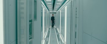 Movie still from “Voyagers” (2021), directed by Neil Burger – A man standing in a hallway of a building; Wide shot, Low angle