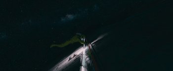 Movie still from “Voyagers” (2021), directed by Neil Burger – A person standing on top of a building at night under a night sky full of stars; Extreme Wide shot, Overhead angle