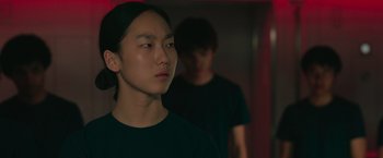 Movie still from “Voyagers” (2021), directed by Neil Burger – A young man standing next to another young man in a dark room; Close Up shot, Over the shoulder angle