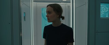 Movie still from “Voyagers” (2021), directed by Neil Burger – A woman in a black t - shirt standing in front of a door; Close Up shot, Over the shoulder angle