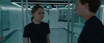 Movie still from “Voyagers” (2021), directed by Neil Burger – A woman standing in front of a mirror in a room; Medium shot, Over the shoulder angle