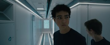 Movie still from “Voyagers” (2021), directed by Neil Burger – A young man standing in a room with a door open; Close Up shot, Low angle