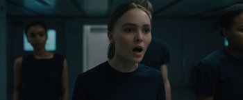 Movie still from “Voyagers” (2021), directed by Neil Burger – A woman with a surprised look on her face; Close Up shot, Over the shoulder angle