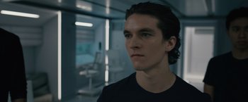 Movie still from “Voyagers” (2021), directed by Neil Burger – A young man in a black t - shirt is looking at the camera; Close Up shot, Low angle