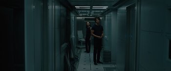 Movie still from “Voyagers” (2021), directed by Neil Burger – A man and a woman standing in a hallway; Wide shot, Low angle