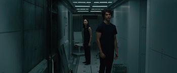 Movie still from “Voyagers” (2021), directed by Neil Burger – A man and a woman standing in a hallway; Medium shot, Low angle