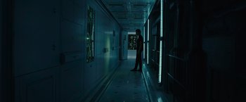 Movie still from “Voyagers” (2021), directed by Neil Burger – A man standing in a dark hallway next to a window; Extreme Wide shot, Low angle