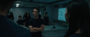 Movie still from “Voyagers” (2021), directed by Neil Burger – A man standing in front of a projection screen; Medium shot, Over the shoulder angle