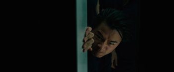 Movie still from “Voyagers” (2021), directed by Neil Burger – A man holding on to a white pole in a dark room; Close Up shot, Low angle